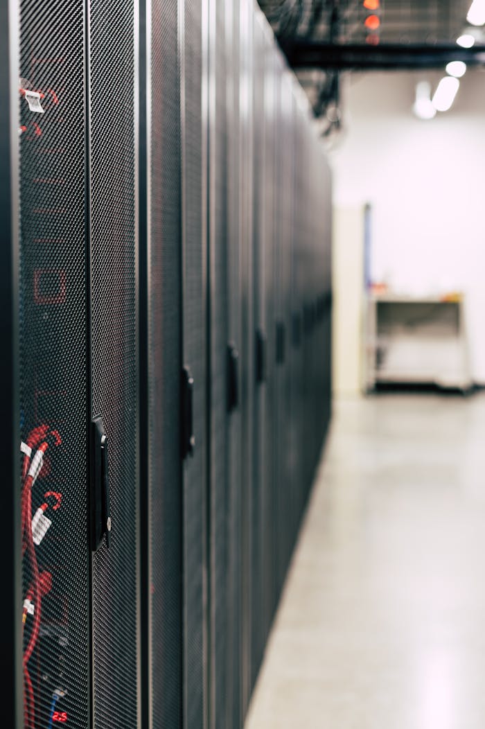 services-03 Metal black cabinets with servers inside with red wires connected standing in row in lighted room